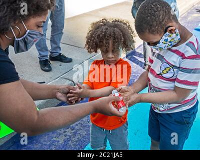 Detroit, United States. 15th June, 2020. Detroit, Michigan - A mother has her children rub sanitizer on their hands during a Black Disabled Lives Matter protest. Credit: Jim West/Alamy Live News Stock Photo