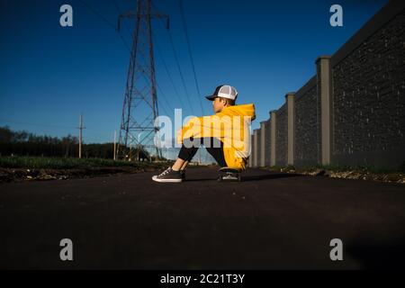 Teen boy sitting on skateboard in the city Stock Photo