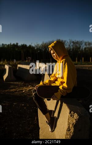 Teen boy sitting on concrete with skateboard Stock Photo
