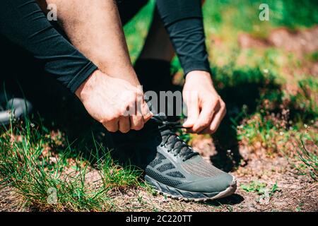 Closeup of attractive young man tying shoelaces before running outdoors Stock Photo