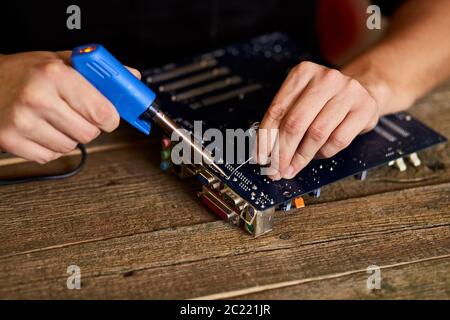 Technician or engineer is focused on repairing circuit board with soldering iron. Stock Photo