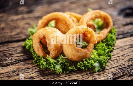 Cripsy onion rings on a lettuce leaf placed on a rustic wood Stock Photo