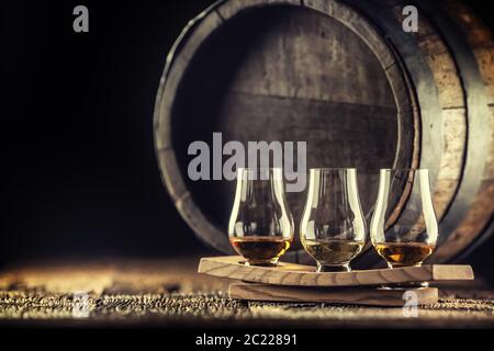 Glencairn whiskey tasting cups on a wooden serving, with a whisky barrel in the dark background Stock Photo
