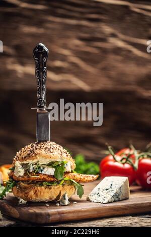 Chicken burger with blue cheese and arugula in a sesame bun on a rustic wood Stock Photo