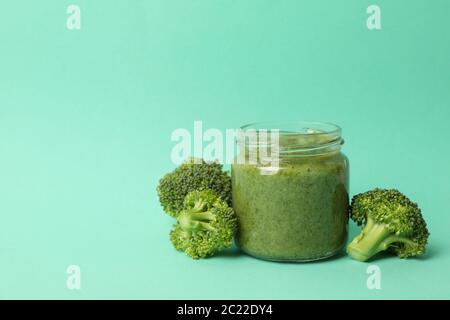 Glass jar with broccoli puree on mint background Stock Photo
