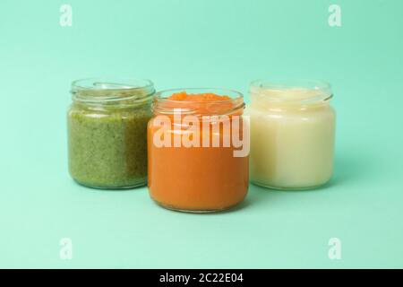 Glass jars with vegetable puree on mint background. Baby food Stock Photo