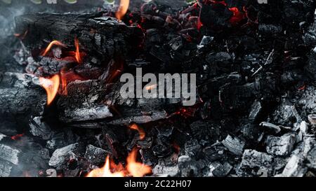 Black coals with fire and sparks in the grill. Preparation for cooking kebabs. Stock Photo