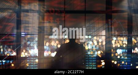 Silhouette of businessman looking on night metropolis, collage with finance info on imaginary screen Stock Photo