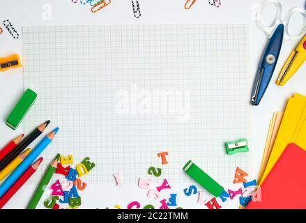 school supplies: multicolored wooden pencils,  notebook, colored paper and  blank white sheet in a check-box, back to school backdrop, copy space Stock Photo