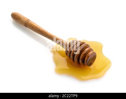 Wooden honey dipper in honey puddle isolated on white Stock Photo