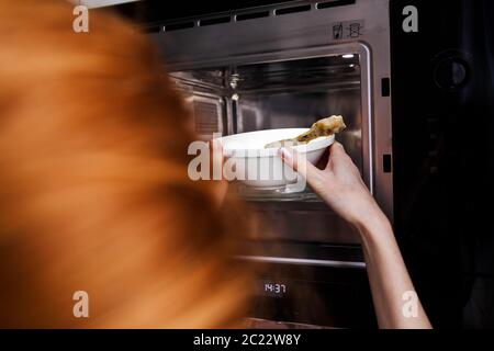 https://l450v.alamy.com/450v/2c22w8y/woman-heats-food-in-the-microwave-kitchen-appliances-built-into-furniture-2c22w8y.jpg