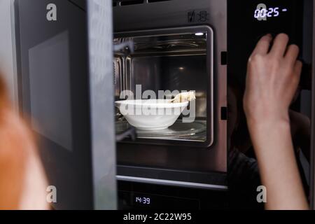 Cooking, heating food in the microwave. Baked potatoes with meat,  vegetables on a white plate in the microwave top view Stock Photo - Alamy