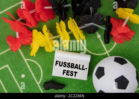 Fussballfest in german language means Soccer Festival. Soccer Ball with flower necklace in the colors of german flag and calendar Stock Photo