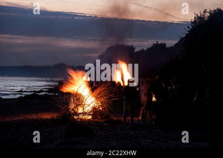 Unrecognisable people celebrating summer solstice with bonfires on beach Stock Photo