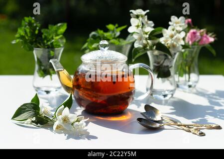 Flowers of rose, jasmine and mint leaves are in a Turkish glass mugs. Ingredients for Herbal Tea. Stock Photo