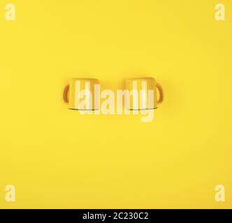 two yellow ceramic cups with a handle on a yellow  background, flat lay, copy space Stock Photo
