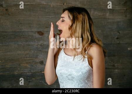 Side view portrait of beautiful young tired woman yawning after overworked. Dressed in cute singlet. Stock Photo