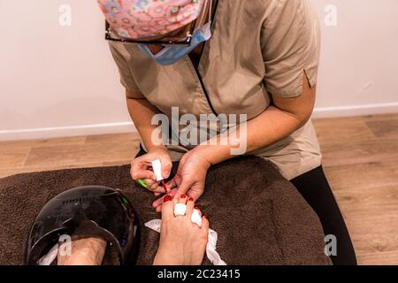 Pedicure 2020 the master is working in protective mask on the period of world pandemic. Pedicure on soft background. Natural cosmetic. Stock Photo