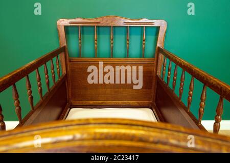 Antique retro wooden baby crib in babies room with green walls modern interior Stock Photo