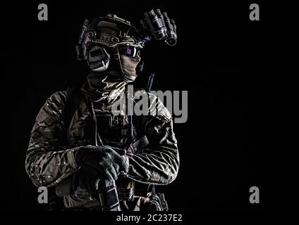 US marine riders shooter, army special forces soldier standing in darkness in mask, battle uniform, quad-tube, four lenses night vision goggles on hel Stock Photo