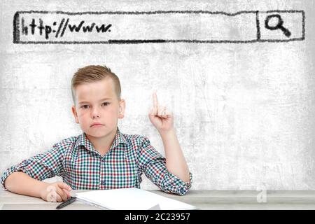 Caucasian school-age boy in a plaid shirt on a light background shows a window with the address of the site Stock Photo