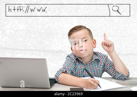 Caucasian school-age boy in a plaid shirt on a light background shows a window with the address of the site Stock Photo