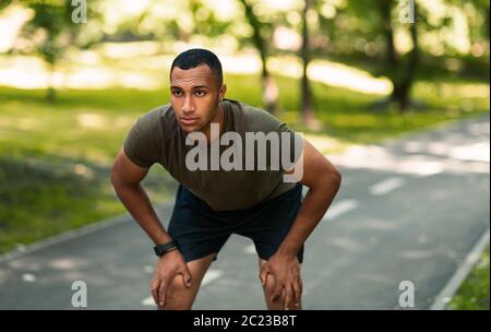 Young African American runner taking break after his training at park