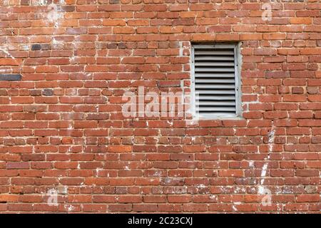 Old brick wall with metal vent insert, crumbling mortar and paint splatters, creative copy space, horizontal aspect Stock Photo