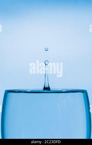 Indoor studio image of a high-speed falling water drop against a blue background Stock Photo