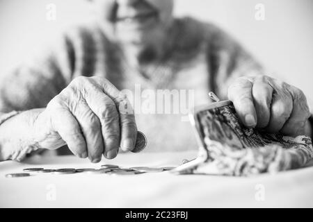 Closeup photo of elderly 96 years old womans hands counting remaining coins from pension in wallet after paying bills. Unsustainability of social tran Stock Photo