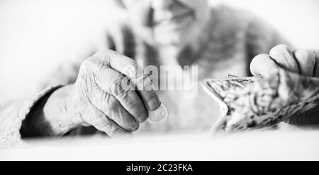 Closeup photo of elderly 96 years old womans hands counting remaining coins from pension in wallet after paying bills. Unsustainability of social tran Stock Photo