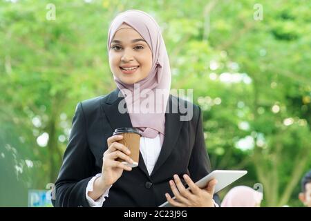 Muslim business woman drinking coffee while going to work in morning. Stock Photo