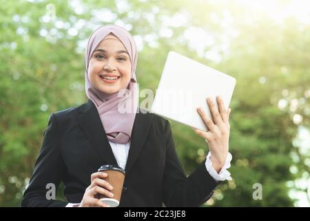 Muslim business woman drinking coffee while going to work in morning. Stock Photo