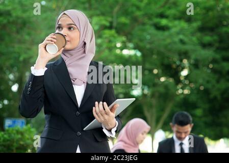 Muslim business woman drinking coffee while going to work in morning. Stock Photo