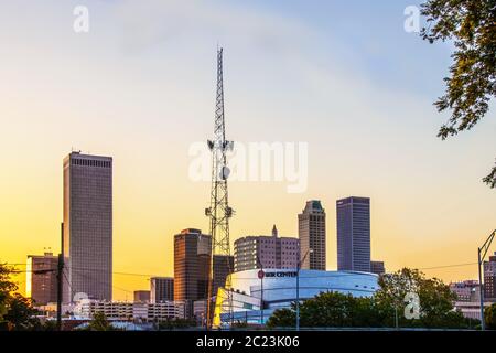 06-14-2020 Tulsa USA BOK Center against downtown skyline at sunrise with yellow sky with communication tower Stock Photo