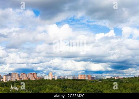 low dense white clouds in blue sky over city on sunny summer day Stock Photo