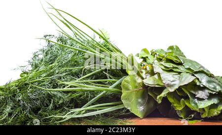 wet fresh bundles of beet greens, scallions and dill on wooden table isolated on white background Stock Photo