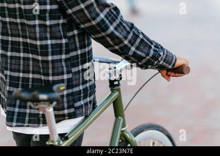 Back view on stylish man standing with bicycle outdoors. Close-up. Stock Photo