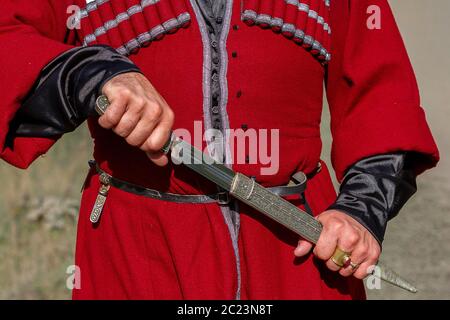 Georgian man in traditional clothes pulling the dagger, Caucasus Mountains, Georgia Stock Photo