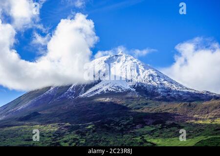 Mount Pico volcano summit covered in snow under blue sky and clouds, in Azores, Portugal. Stock Photo