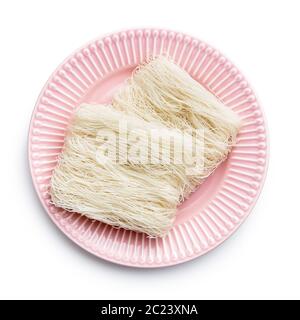 Uncooked white rice noodles on pink plate isolated on white background. Stock Photo