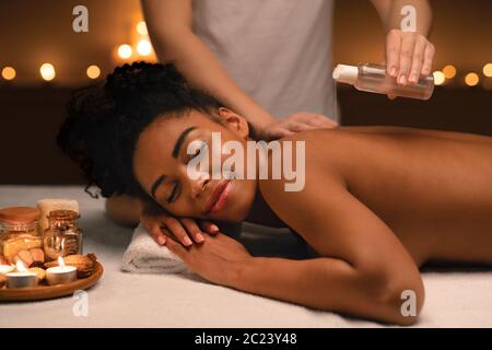 Relaxed african woman enjoying aromatherapy and massage at spa Stock Photo