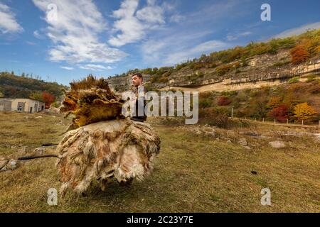 Local man stacking sheep skins after they were dried in the sun, in Chiatura, Georgia Stock Photo