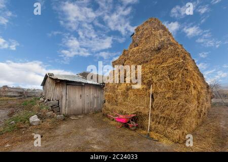 Haystack and pink wheelbarrow in village, Georgia Stock Photo