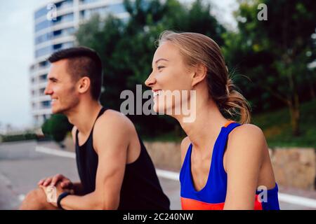 Young beautiful couple practicing sport outdoors, stretching, doing exercises, enjoying healthy lifestyle. Outside. Stock Photo