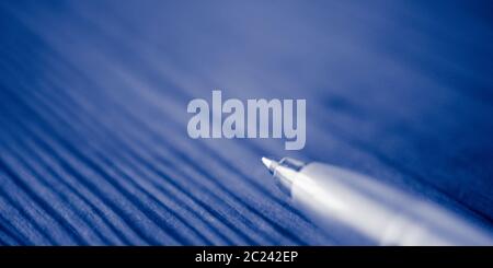 Ball pen on the blue wooden table. Macro photo, side view. Stock Photo