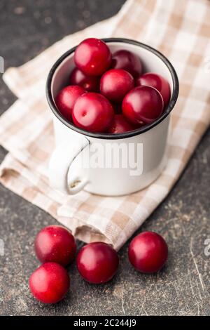 The red cherry plums fruit in mug. Stock Photo
