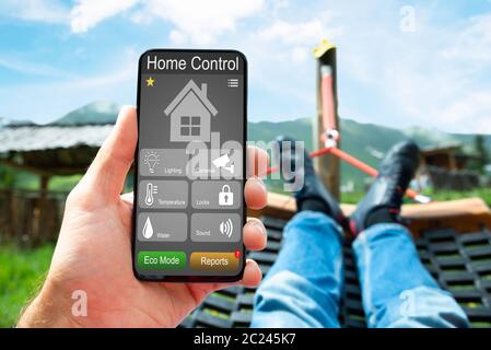 Man Lying In Hammock Using Smart Home And Security System App Stock Photo