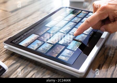 Young Male Editor Searching Photos On Tablet In Office Stock Photo