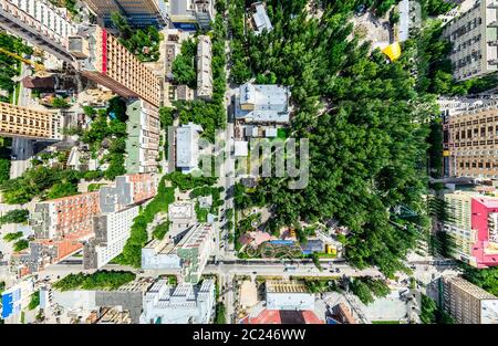Aerial city view with crossroads and roads, houses, buildings, parks and parking lots. Sunny summer panoramic image Stock Photo